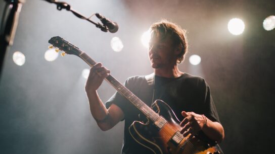 Musician playing the guitar and singing under a spotlight onstage